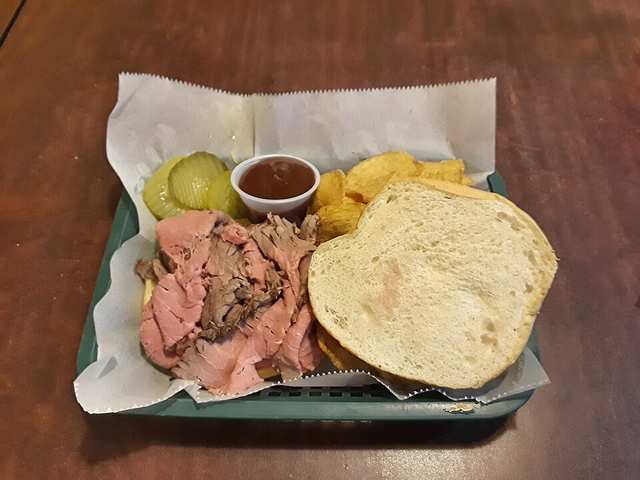 Pit beef sandwich with Old Bay potato chips, pickes, and barbecue sauce at Pit Boys in Annapolis, Ma